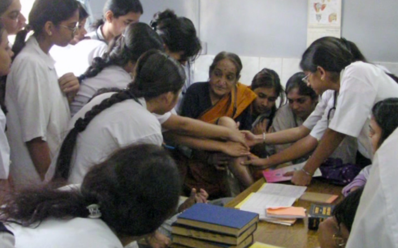 Homöopathie Zürich - Indische Studenten und Studentinnen sitzen um eine indische Patientin.
